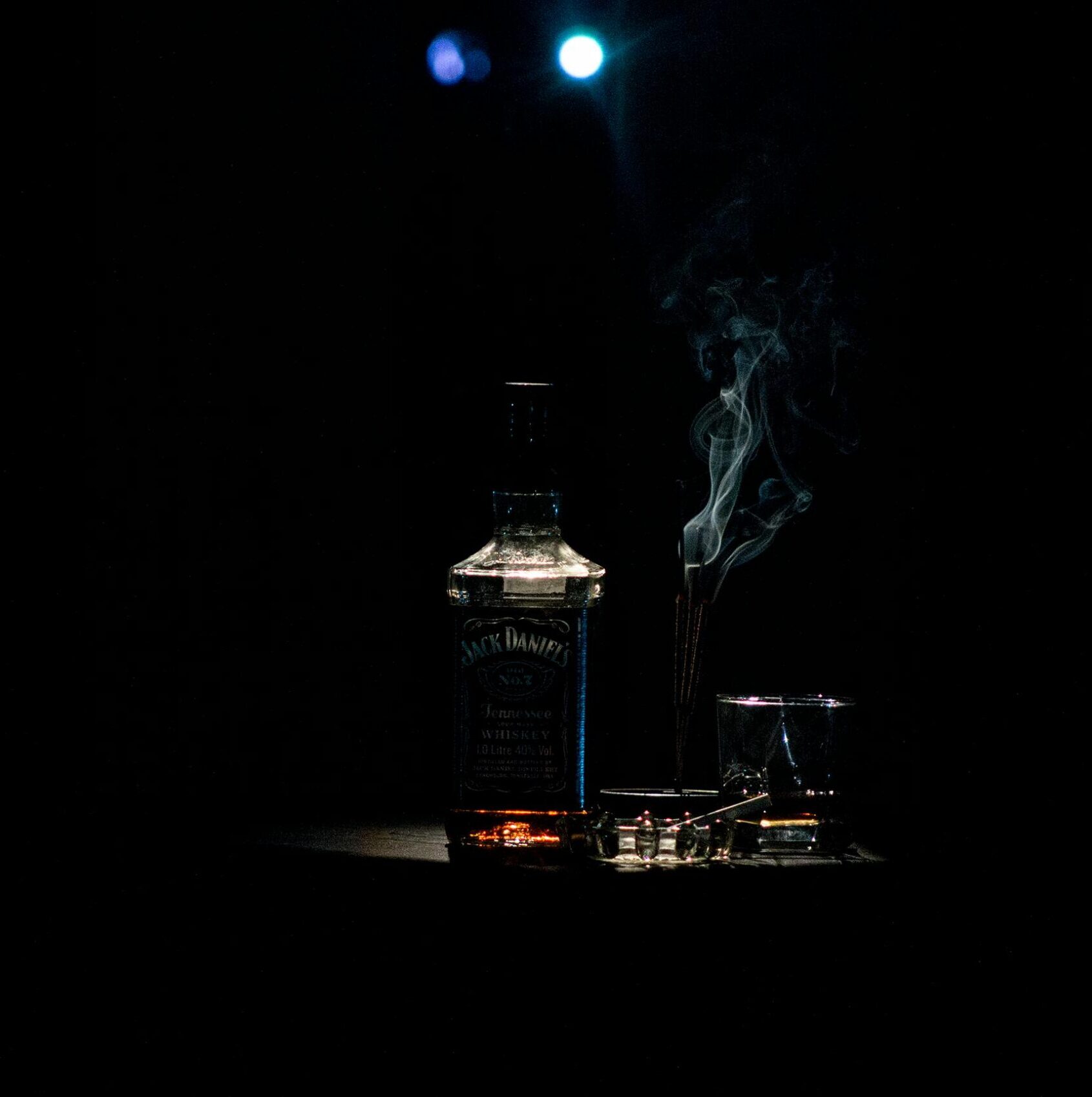 A dramatic whiskey bottle with smoke on a dark background, accented by soft lighting.